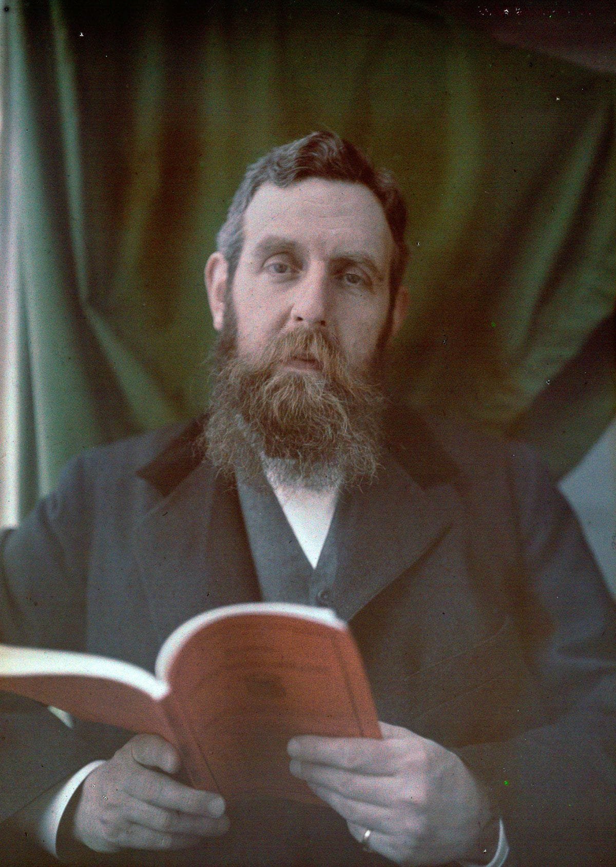 Retrato autocromo de un hombre con barba larga leyendo un libro