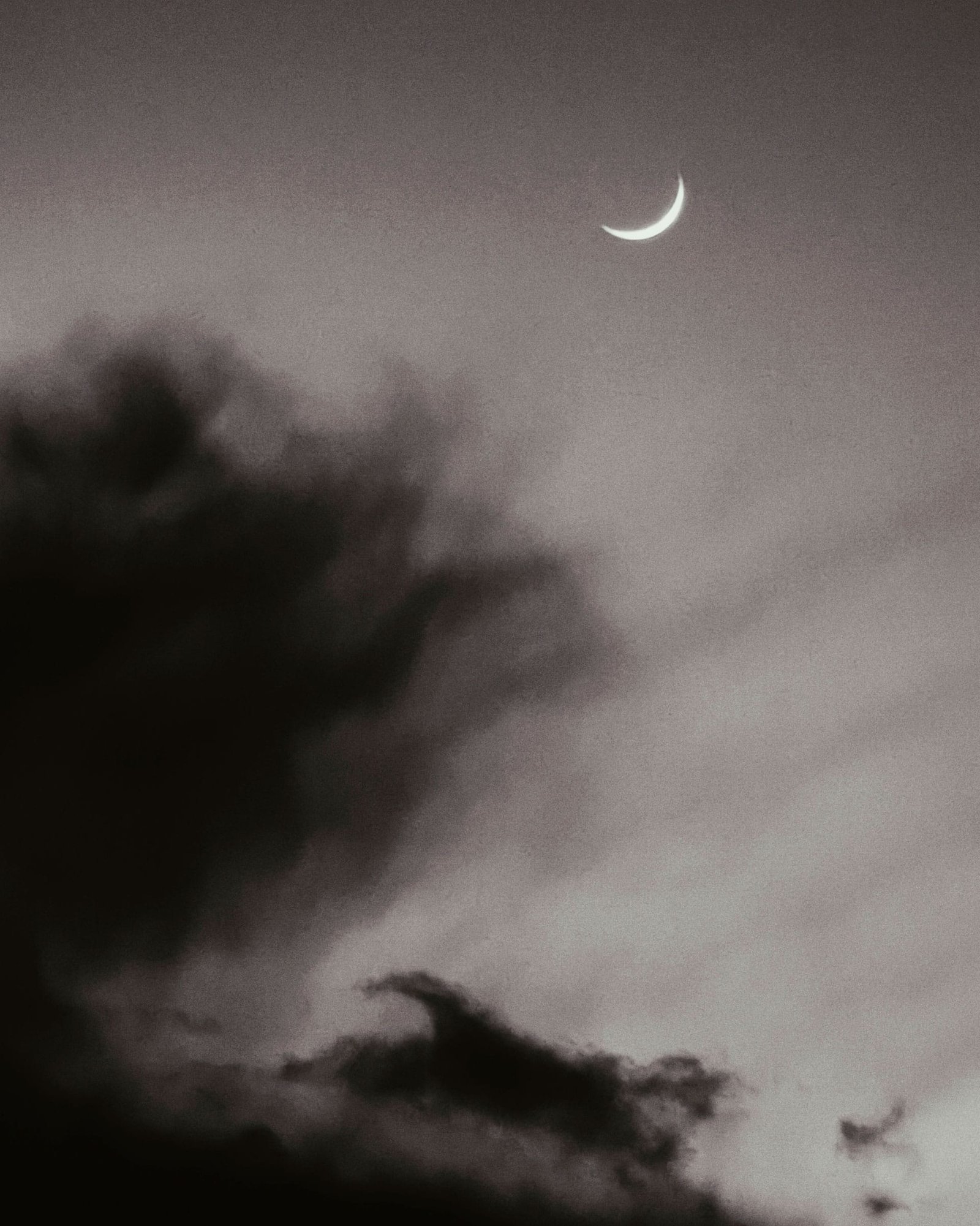 Luna creciente entre nubes oscuras en el cielo nocturno