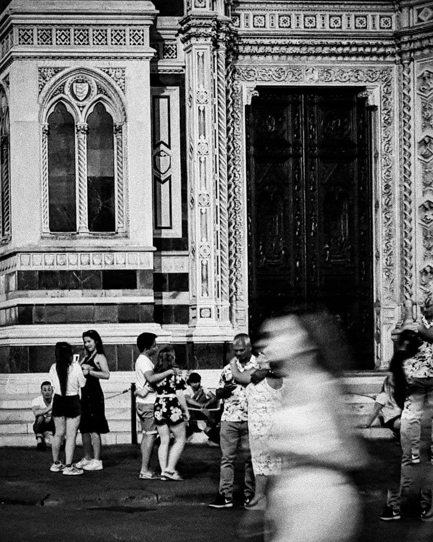 Fachada ornamentada de un edificio con turistas en la calle, en blanco y negro